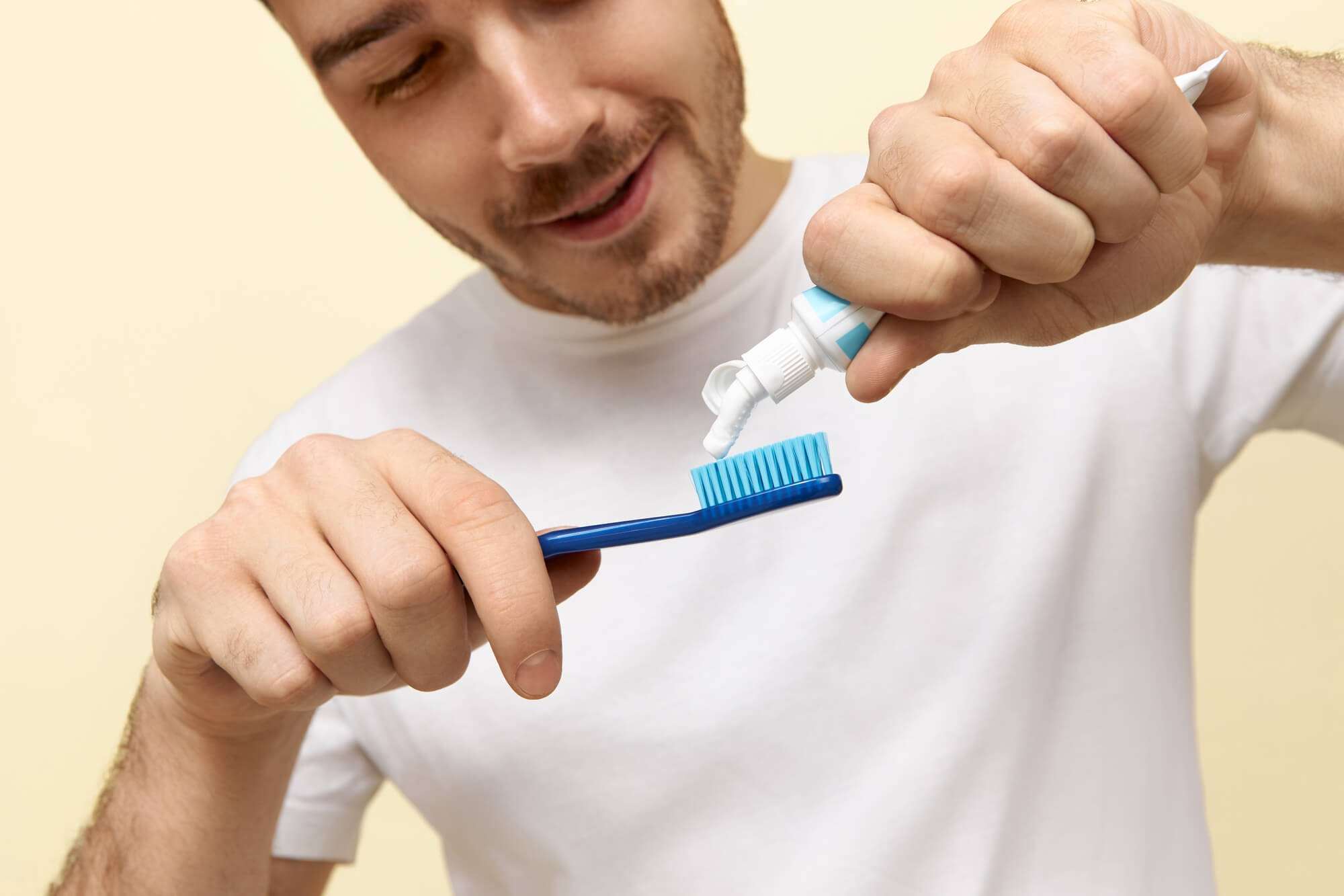 man white t-shirt squeezing paste toothbrush