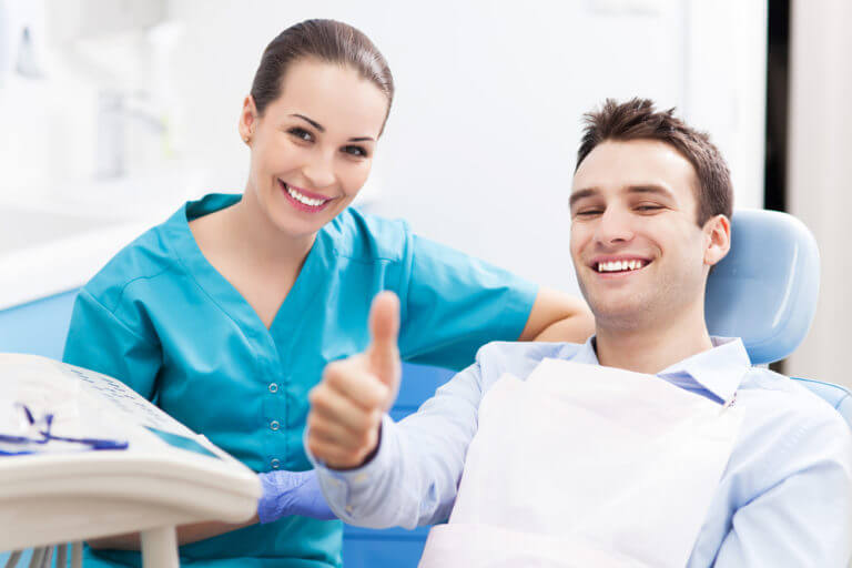 Man gives thumbs up in dental chair after passing oral cancer screening