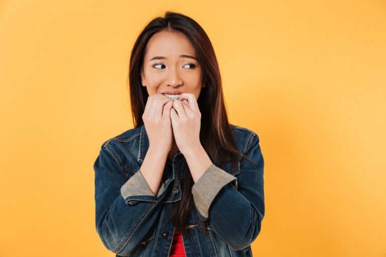 woman biting her nails and experiencing the effects on her teeth