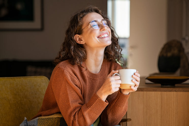 Woman drinking coffee and contemplating the best time to brush her teeth