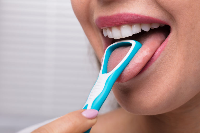 Woman cleaning her tongue to get rid of bad breath