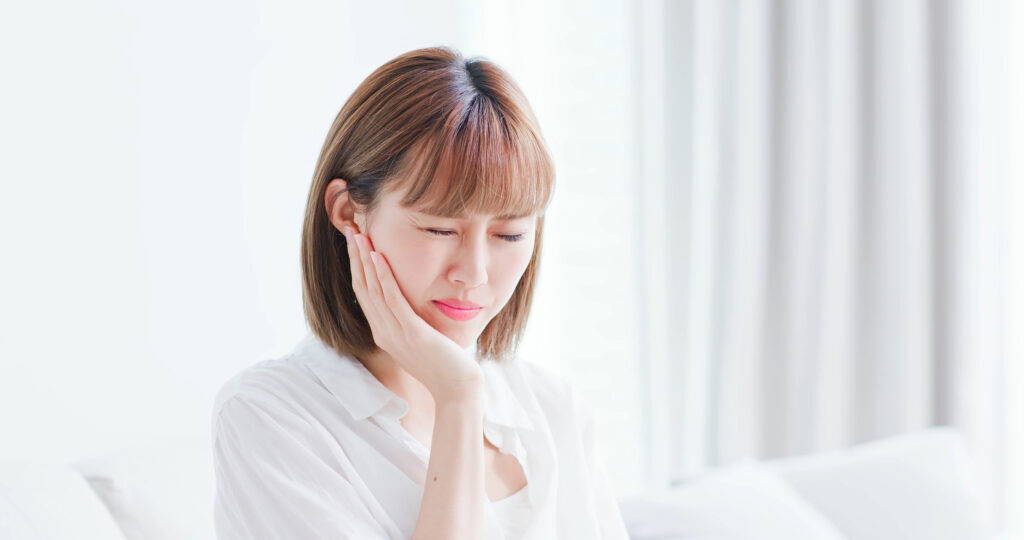 women touching her gums in discomfort